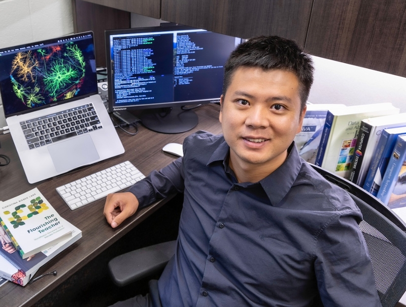 Guimo Guo in his office at his desk with computer monitors illustrating graph mining examples