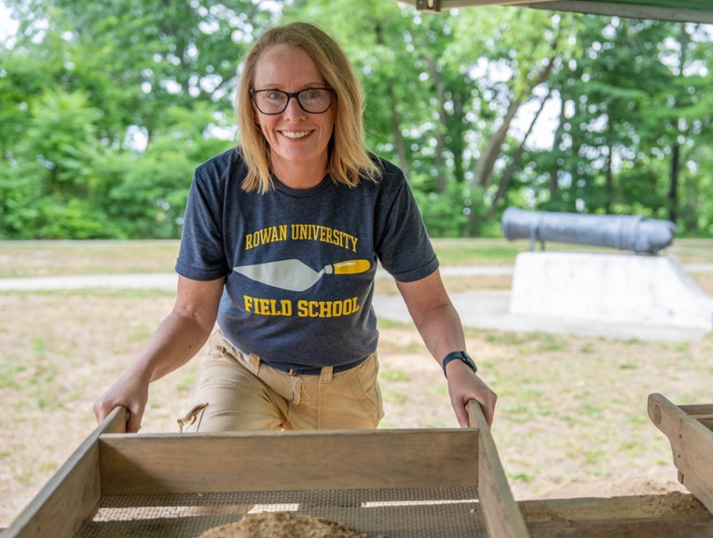 Jennifer Janofsky sifts excavated material under an outdoor canopy.