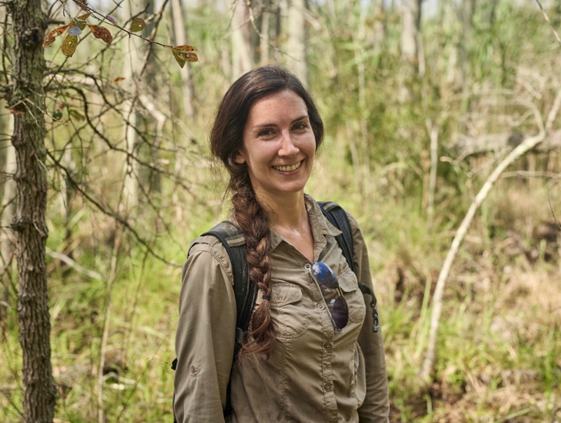 Researcher Jennifer Walker stands in tall grass doing field work.
