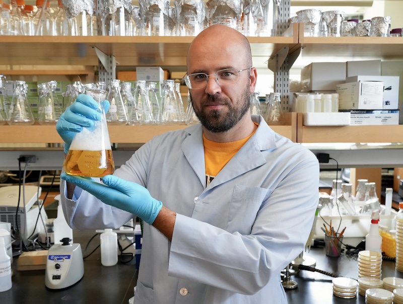 Rowan researcher Matthew Farber holding a flask of beer in a lab setting