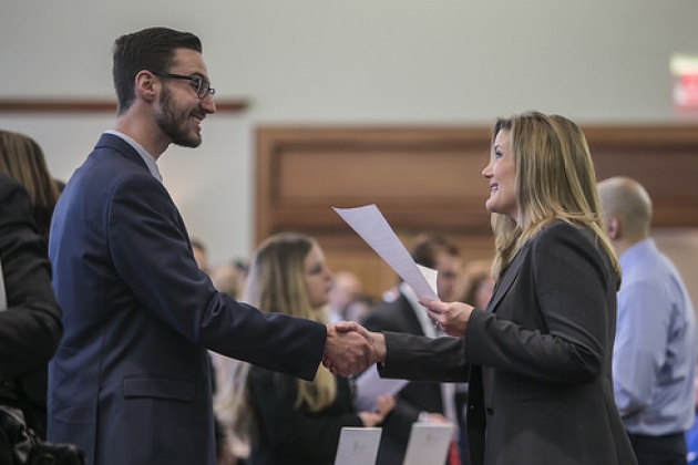 A man and woman in dark suits shake hands