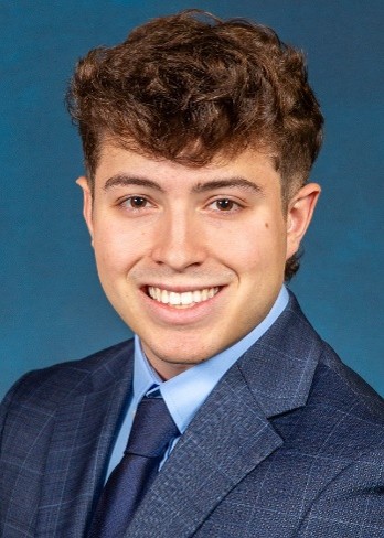 COlton Pelletier smiles while wearing a blue suit