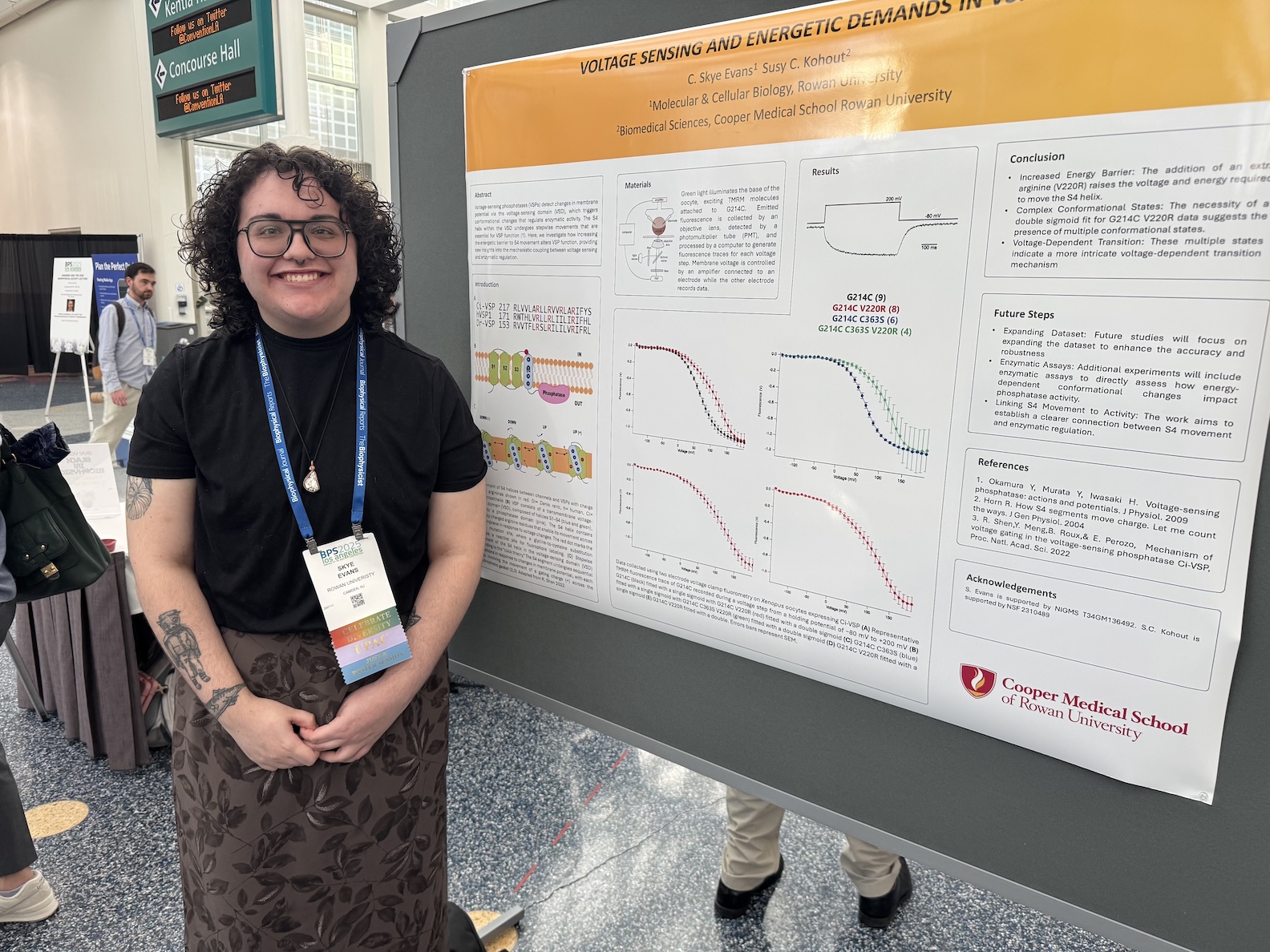 Skye Amann standing in front of their poster at the JUST-B poster session at BPS 2025